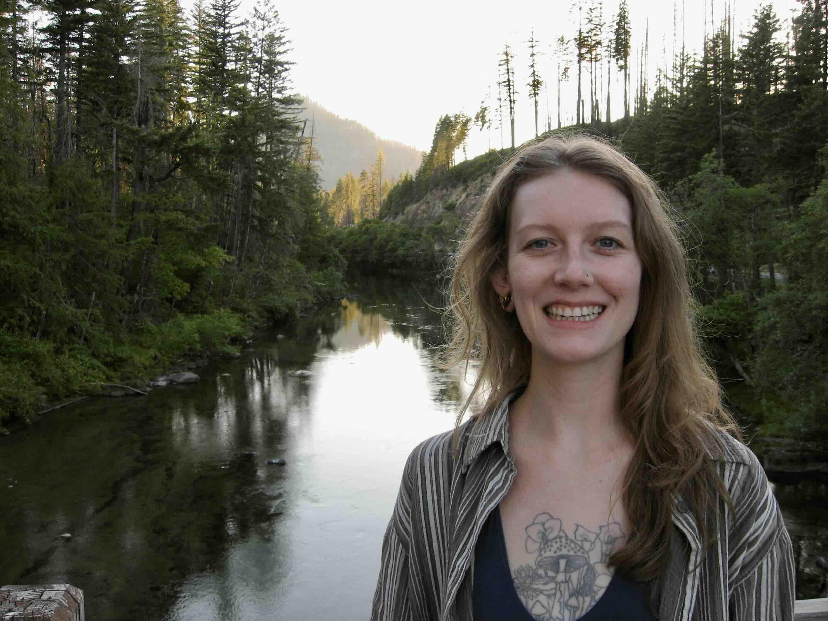Kylie smiling in front of a forest lake